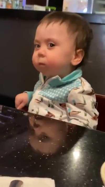 Kid is determined, but struggling, to endure first taste of spicy pepper.