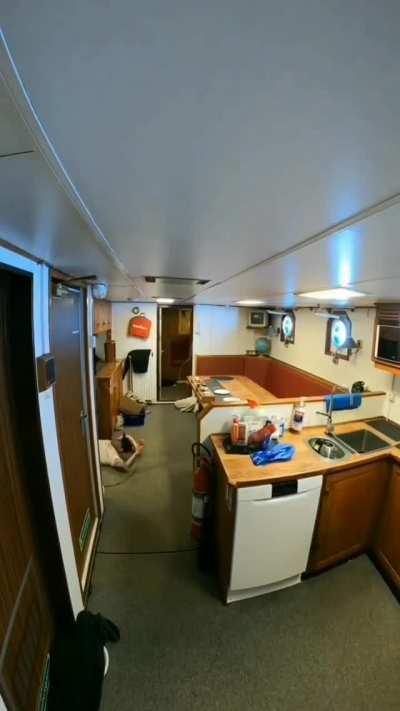 A crew member inside a ship struggling with waves in the middle of the ocean