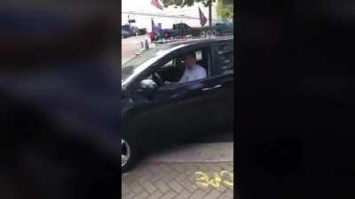 Anti-Trump driver heckles pro-Trump supporters on sidewalk, appears to spit on Trump flag, then gets spit on by Trumper, then immediately crashes into a light-pole, then gets investigated by police