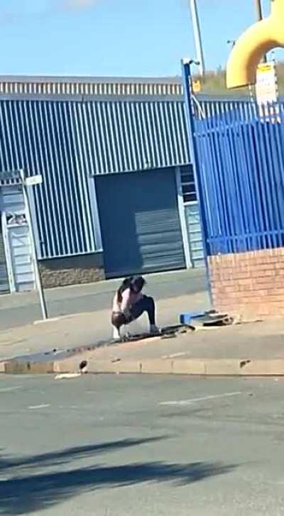 Cleaning her nether regions using gutter water.