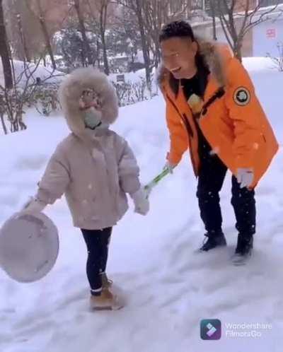 kid tries throwing snow at her daddy