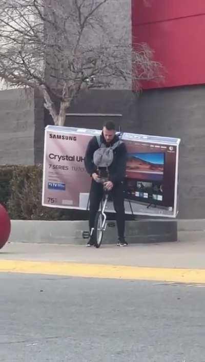 Dude rides off on a unicycle carrying a new 75