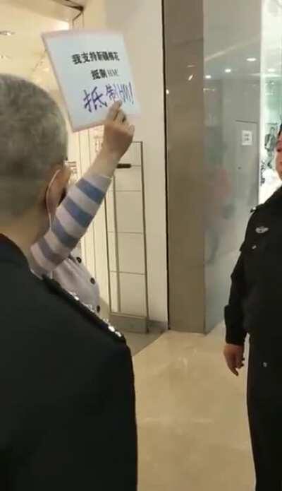 HM门口举牌支持新疆棉被警察带走了