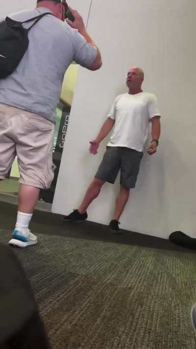 Dude at an airport for whatever reason, (possibly drunk) decides to use another resting man as a seat