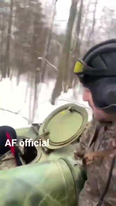 Ukrainian artillerymen ride their 2S1 Gvozdika 122mm self-propelled howitzer through snowy woods.