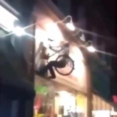 Man climbs on bike sign