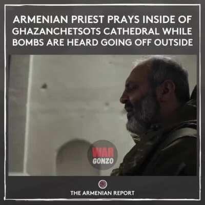 Armenian priest prays inside a church while bombs are heard outside