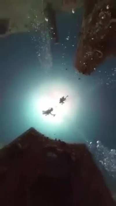 Scuba diver dropping a GoPro to the sea floor through a shipwreck