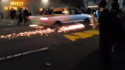 rioters try blocking truck with motorcycle to pull the driver out, it goes pretty much how you think it would