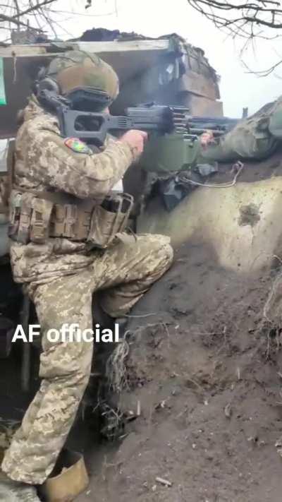 Ukrainian soldier fires a PKM from his trench parapet.