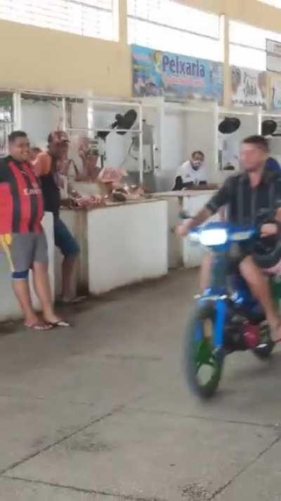 Man with motorized bike at market takes a tumble