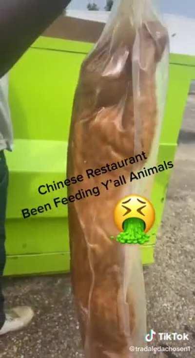 Man searches in garbage bin behind Asian Restaurant