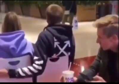 A guy helping another guy put his arm around a girl.