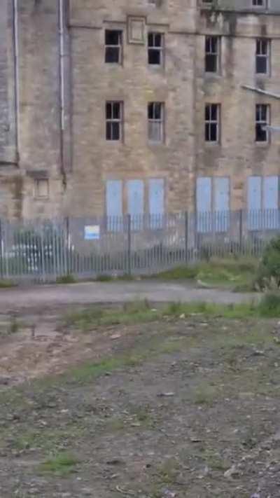 Went to the Hartwood Insane Asylum in the UK and captured something peeking out of the top left window and moving away to the left side. The whole building is locked and the lower floor windows are far too high to reach and even if someone got inside the 