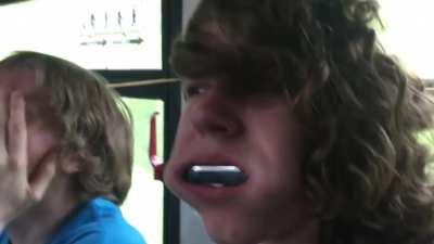 Putting a harmonica in his mouth.