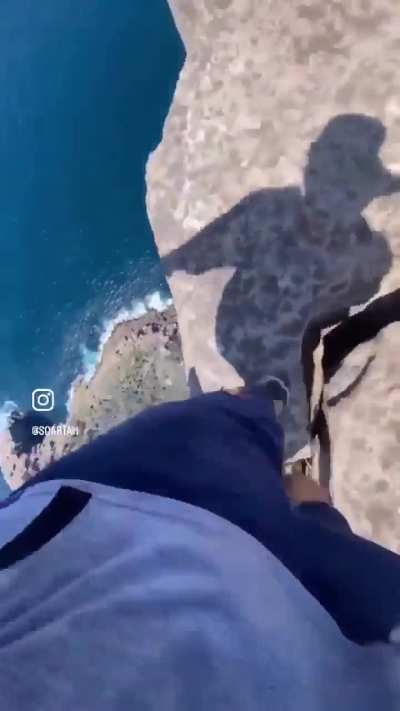 Man jumps from rock to rock over cliff