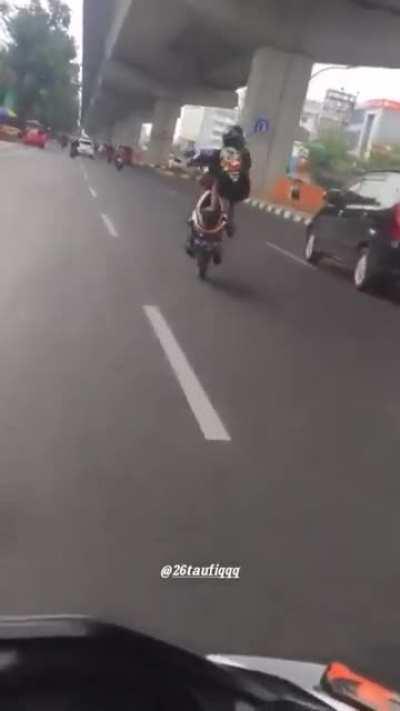 Guy dances around his motorcycle on a busy road