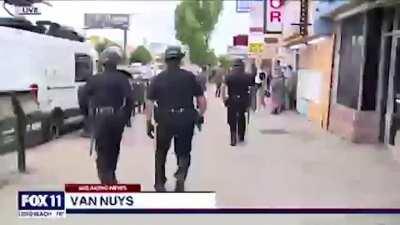 Police apprehend black store owners who are trying to stop white looters