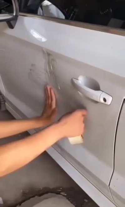 Using packing tape to remove a car dent.