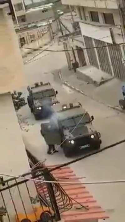Israeli soldier pulls the pin of a sound grenade inside an armored vehicle.