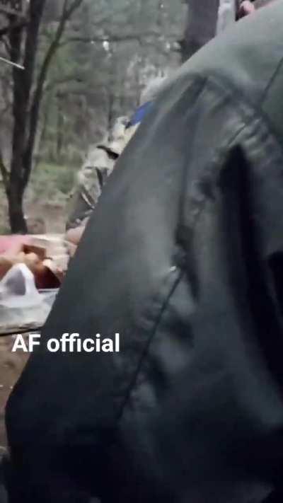 Ukrainian soldiers happily queue for their meal at a field kitchen in the woods.