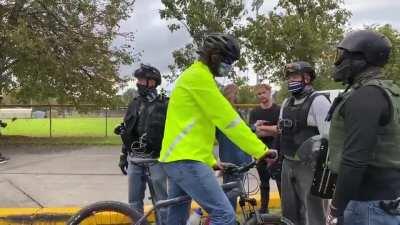 A bicyclist is stopped by Proud Boys, a kind of checkpoint before letting him pass.