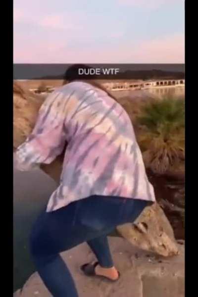 Throwing a log of wood standing on the edge of a lake