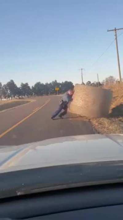 A Missouri Highway Patrol officer clears the road by lifting a 300kg bale of hay