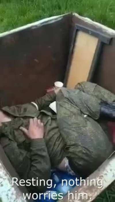 Drunk russian soldier sleep in the trash container.