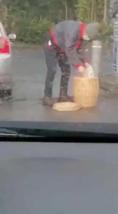 Man filling a trash bag with petrol and placing it in a basket in the boot of his car