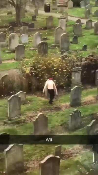 A lone woman getting groovy in a cemetery.
