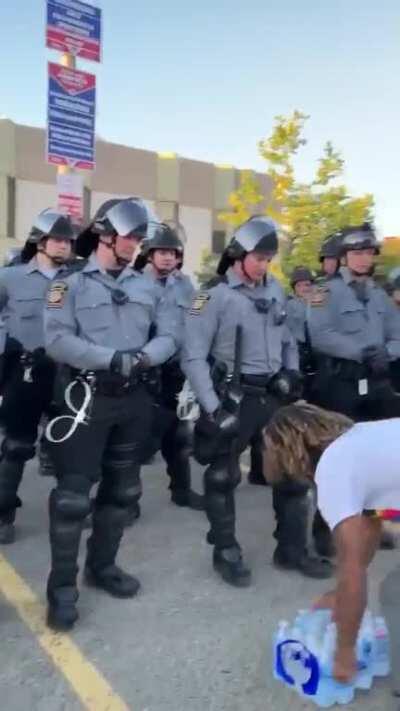 One of the organizers of a peaceful demonstration in Pittsburgh gives the state police water that was donated to protesters