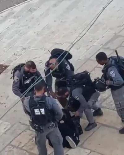 IOF cowards surround, detain and abuse a Palestinian woman as she lays on the ground weeping.