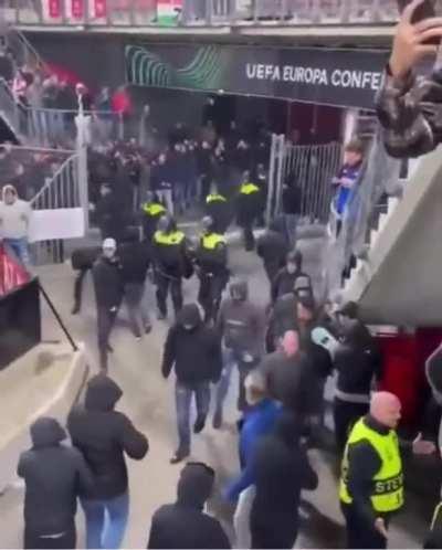 2 West Ham fans hold back the entire group of AZ Ultras (while stewards hold back our players in the background)