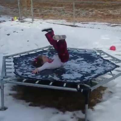 Kid jumps on a trampoline covered in ice