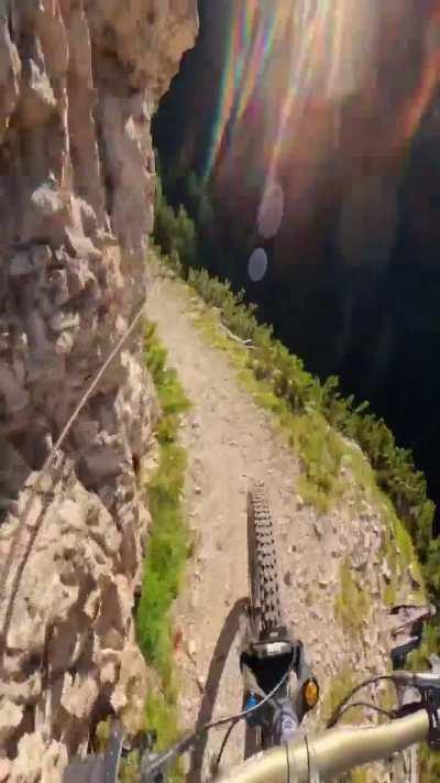 Cyclist rides on a mountain footpath for a video project.