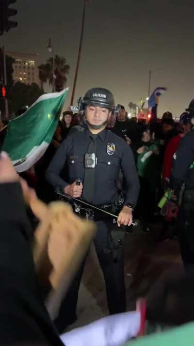 Cop checks out protester while he dances in front of him at the Ant-ICE Protest in Los Angeles