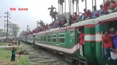 Train full of people passing under a bridge while another train full of people passes over the bridge.