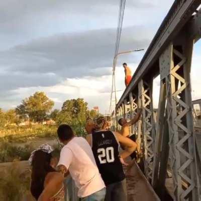 Suben a la estructura de un puente para saltar al río, uno se da un planchazo en el río y el otro se da un planchazo en el pavimento 