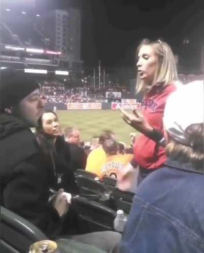 Woman hocks an impressively accurate loogie on a guy's face during a baseball game.