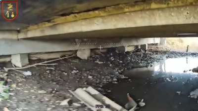 Russian FPV drone operator targets pair of Ukrainian soldiers hiding under a damaged bridge structure.