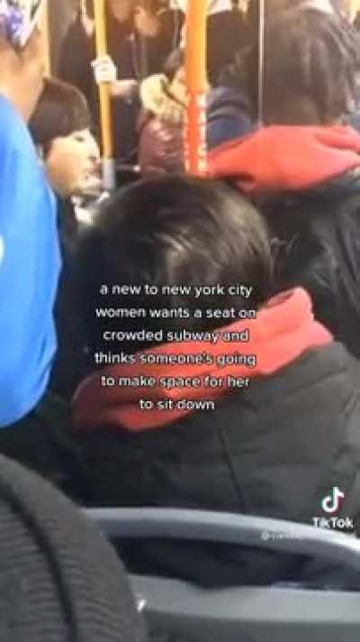 A woman requests a seat on a crowded train.