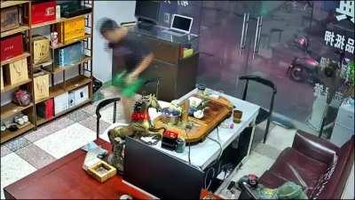 Focused on his phone while placing kettle with hot water on desk