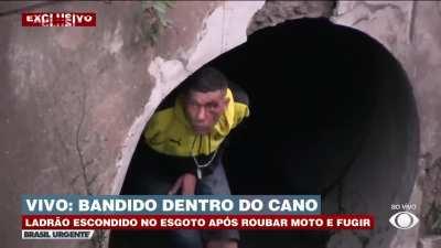 Thief realizes he is being filmed by a TV crew while hiding in a sewer pipe