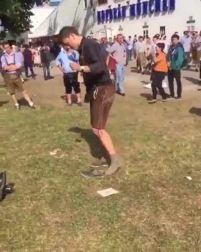 This dude is hammered-drunk and trying to to put his shoe back on. A huge crowd gathers to cheer for him hoping he successfully puts on his shoes.