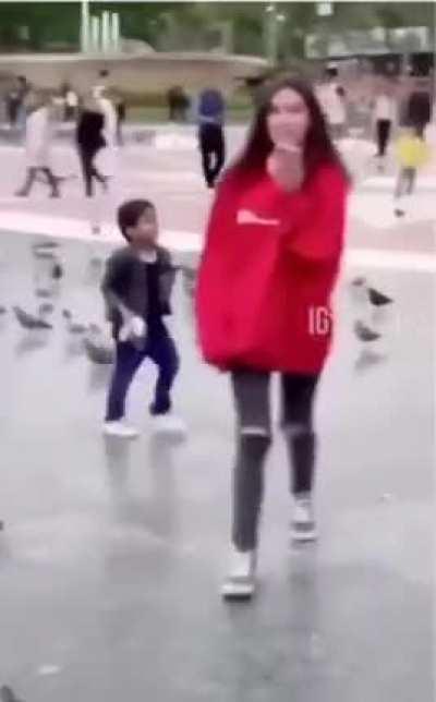 Kid walking around the square throwing pigeons at people