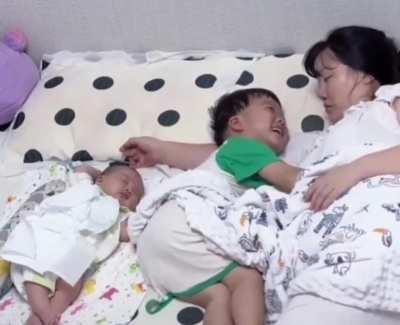 He wanted to cuddle his mum and wasn't going to let his baby sibling stop him. 