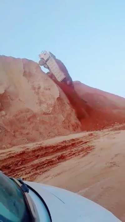 Truck with heavy load slides down hill and flips