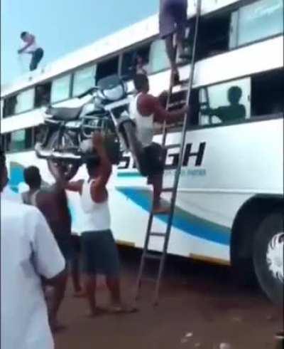 Carrying a motorcycle up a ladder like it's nothing!