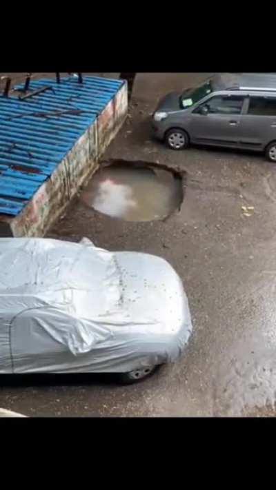 Concrete ground breaks open, sinking a parked car in underground water